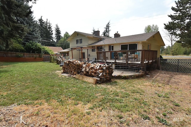 rear view of house featuring a wooden deck and a yard