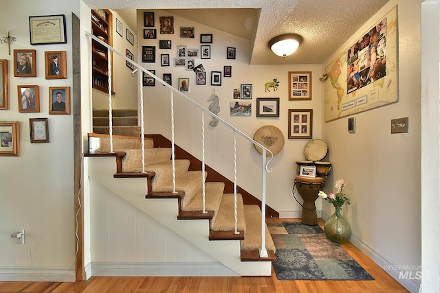 stairway featuring hardwood / wood-style flooring and a textured ceiling