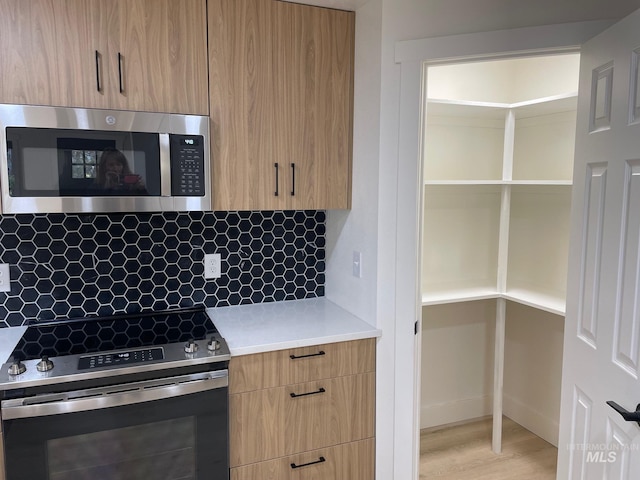 kitchen with stainless steel appliances, modern cabinets, light countertops, and decorative backsplash