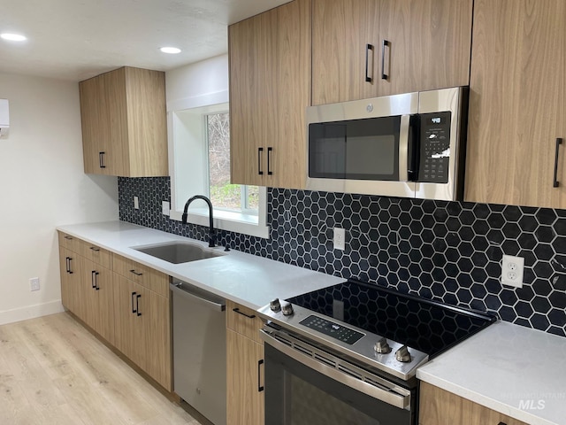 kitchen featuring appliances with stainless steel finishes, light countertops, a sink, and backsplash