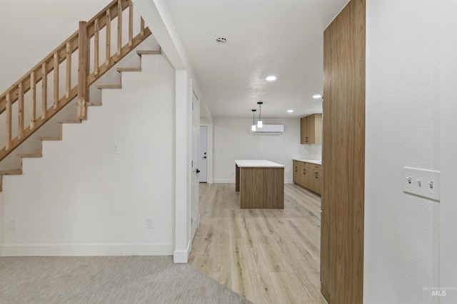 kitchen featuring recessed lighting, a wall mounted AC, a kitchen island, light wood-type flooring, and baseboards