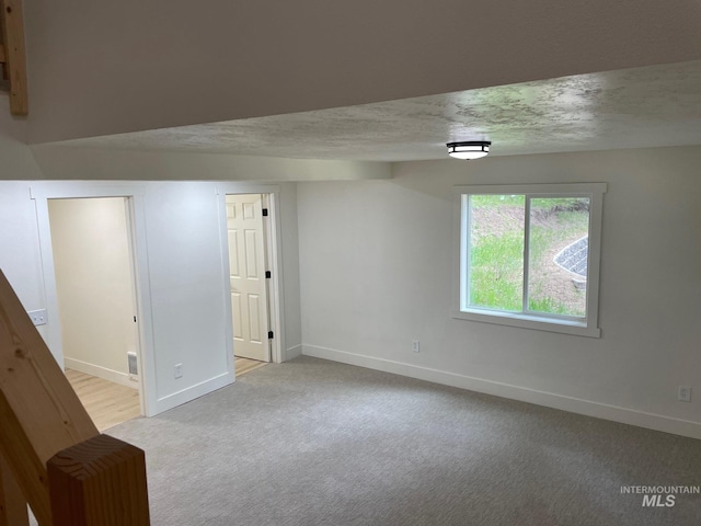 carpeted empty room featuring visible vents, a textured ceiling, and baseboards