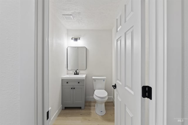 bathroom featuring visible vents, toilet, wood finished floors, a textured ceiling, and vanity