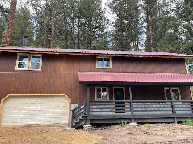 view of front of house featuring a garage, covered porch, and metal roof