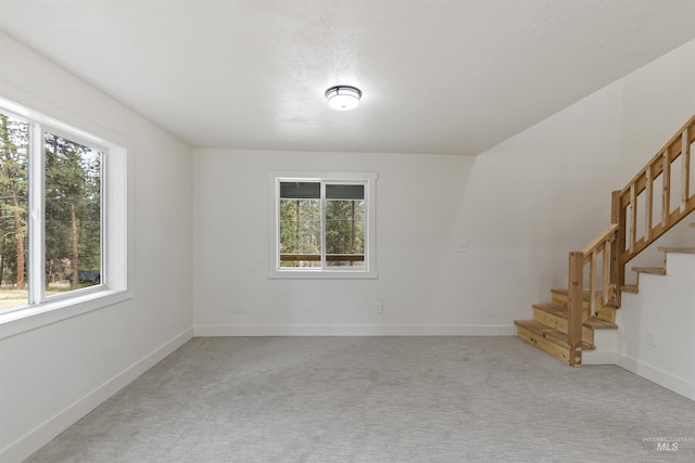 empty room with light carpet, baseboards, and stairs