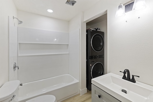 bathroom featuring toilet, shower / bath combination, wood finished floors, vanity, and stacked washer / drying machine