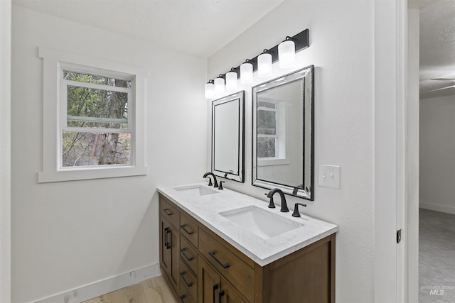 full bath with double vanity, baseboards, and a sink