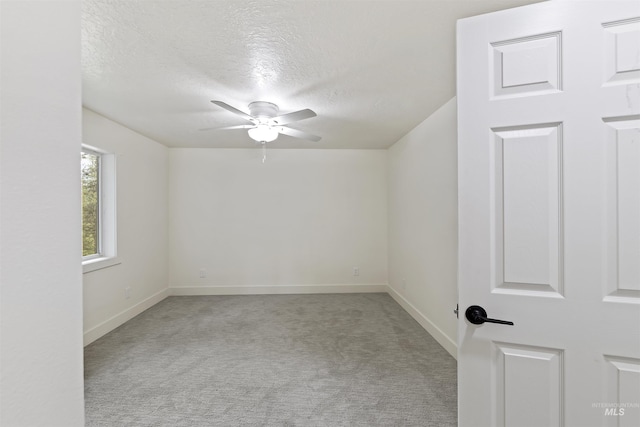 carpeted empty room featuring ceiling fan, a textured ceiling, and baseboards