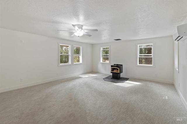 unfurnished living room with a textured ceiling, a ceiling fan, a wood stove, and light colored carpet