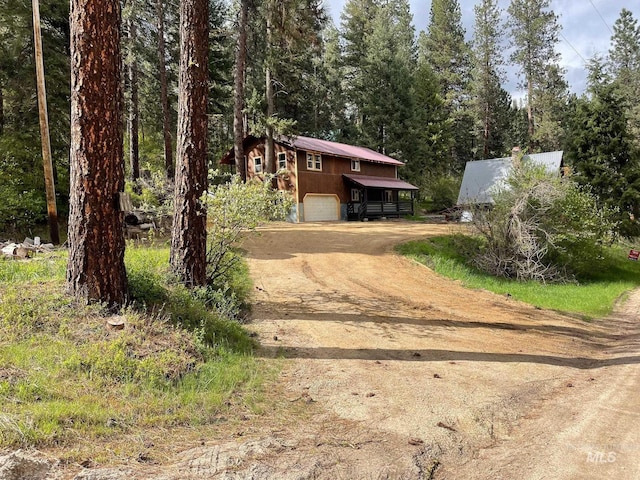 view of front of house featuring a garage, driveway, and a forest view