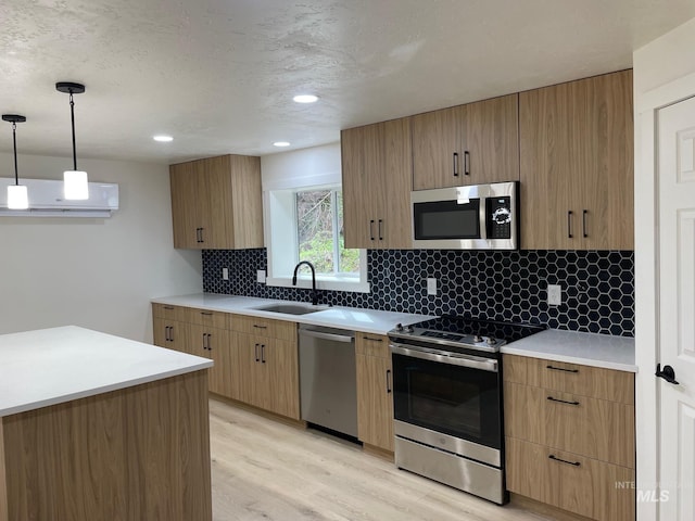 kitchen featuring light wood-style flooring, a sink, appliances with stainless steel finishes, decorative backsplash, and a wall mounted air conditioner