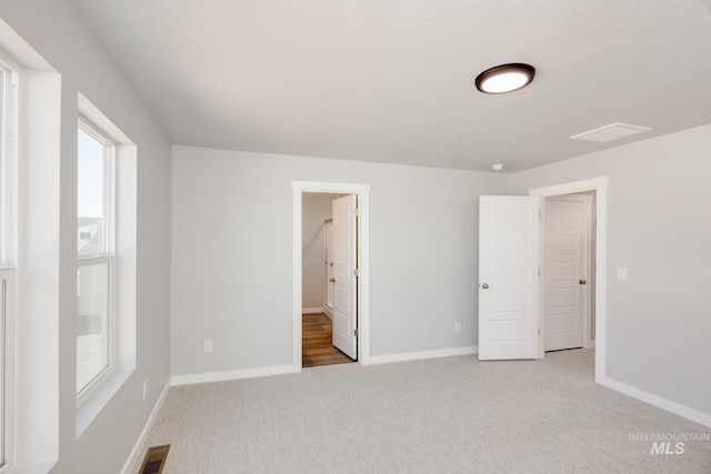 unfurnished bedroom featuring carpet floors, baseboards, and visible vents