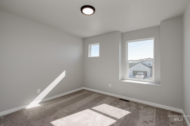 unfurnished room with carpet, visible vents, and baseboards