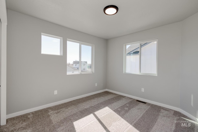 carpeted empty room with visible vents and baseboards