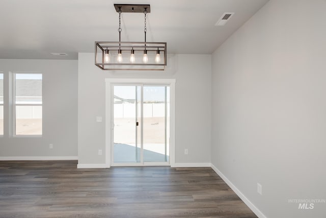 unfurnished dining area with dark wood-type flooring, visible vents, and baseboards