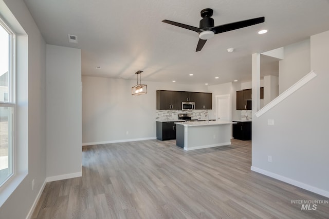 kitchen with visible vents, appliances with stainless steel finishes, light countertops, light wood-style floors, and backsplash