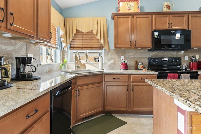 kitchen with light stone counters, black appliances, decorative backsplash, and sink