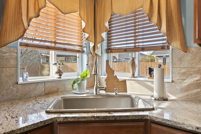 kitchen with light stone counters, decorative backsplash, and sink