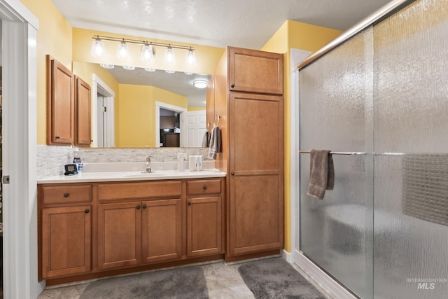 bathroom featuring an enclosed shower, vanity, and decorative backsplash