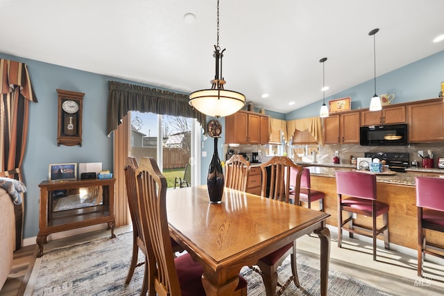 dining area with vaulted ceiling and light hardwood / wood-style flooring