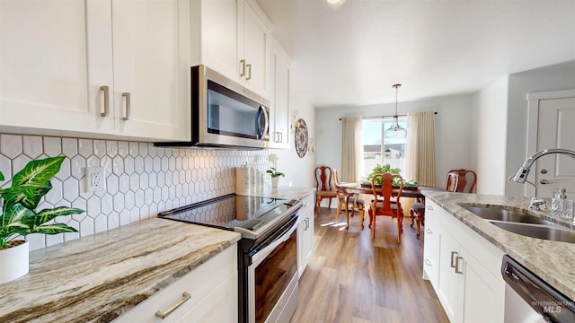 kitchen featuring light wood finished floors, white cabinetry, stainless steel appliances, and a sink