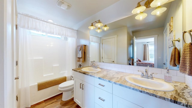 bathroom with double vanity, backsplash, toilet, and a sink