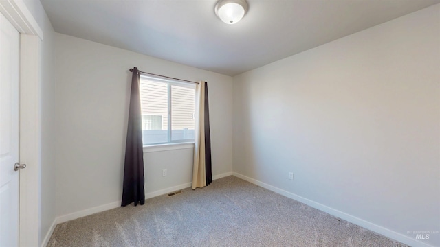 unfurnished room with visible vents, light colored carpet, and baseboards