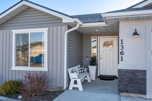 doorway to property with a porch, board and batten siding, and a shingled roof