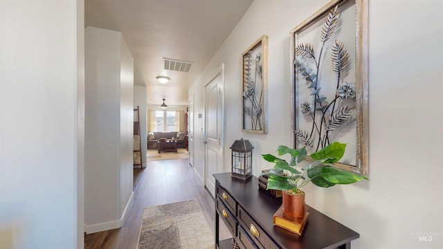 hallway featuring visible vents, baseboards, and wood finished floors