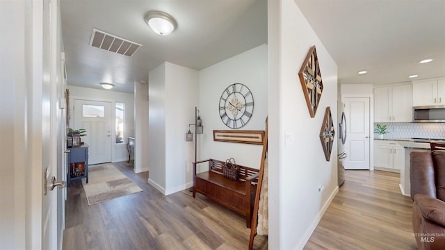 hall featuring wood finished floors, visible vents, and baseboards