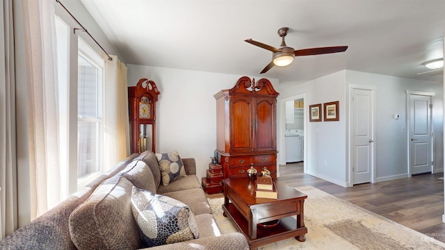 living room featuring ceiling fan, baseboards, wood finished floors, and washer / clothes dryer