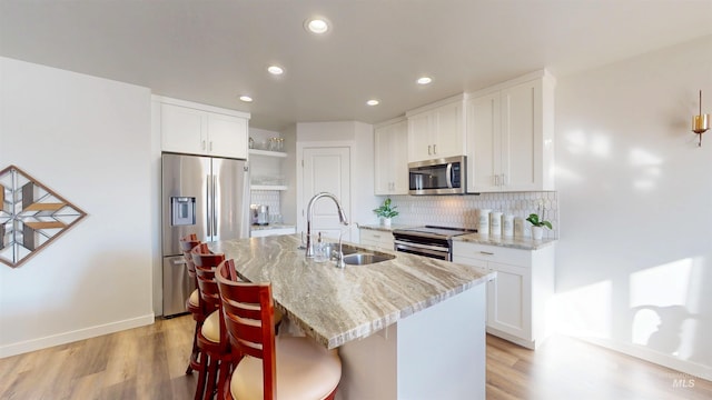 kitchen featuring a sink, light stone countertops, decorative backsplash, appliances with stainless steel finishes, and open shelves