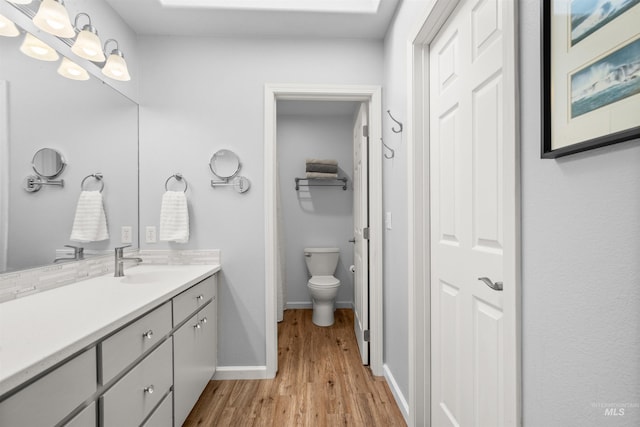 bathroom with hardwood / wood-style floors, vanity, and toilet