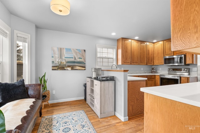 kitchen featuring kitchen peninsula, stainless steel appliances, and light wood-type flooring