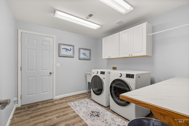 washroom with washer and dryer, light hardwood / wood-style flooring, and cabinets