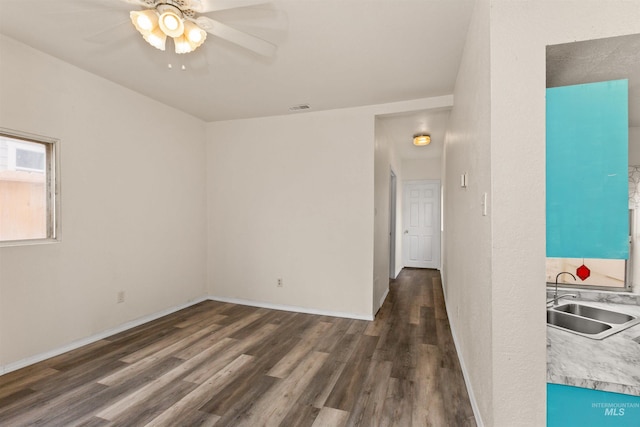unfurnished room featuring a sink, wood finished floors, ceiling fan, and baseboards
