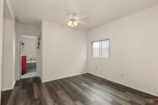 empty room featuring ceiling fan, dark wood-style floors, attic access, and baseboards