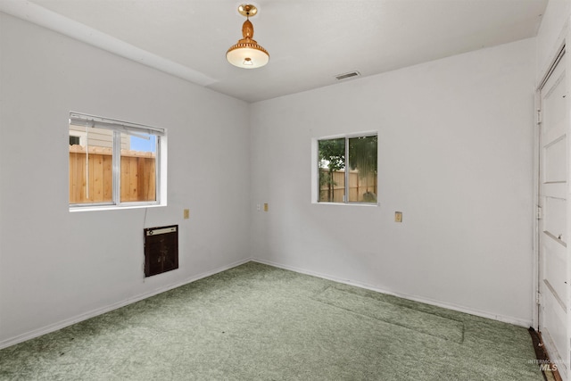 carpeted empty room featuring baseboards and heating unit