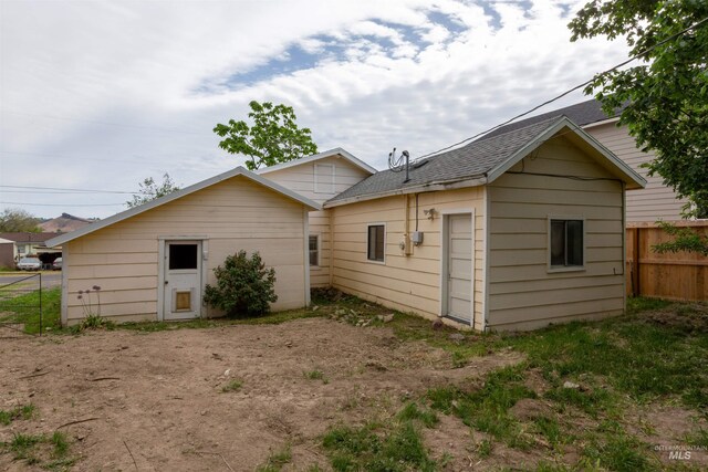 rear view of property featuring fence and roof with shingles