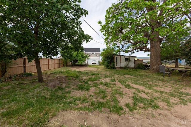 view of yard with fence, an outdoor structure, and a storage unit