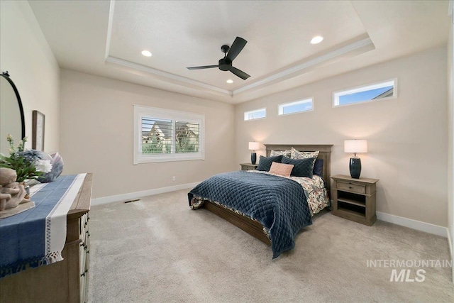 bedroom featuring light carpet, ceiling fan, and a tray ceiling