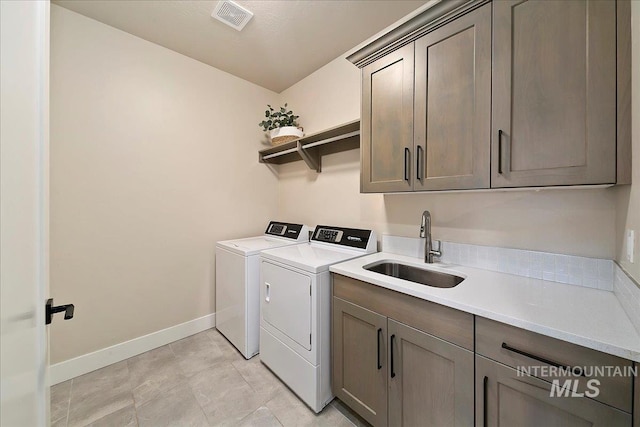 clothes washing area featuring cabinets, light tile patterned floors, washer and clothes dryer, and sink