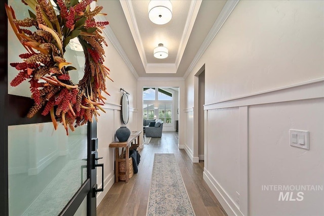 interior space with ornamental molding, a tray ceiling, and hardwood / wood-style flooring