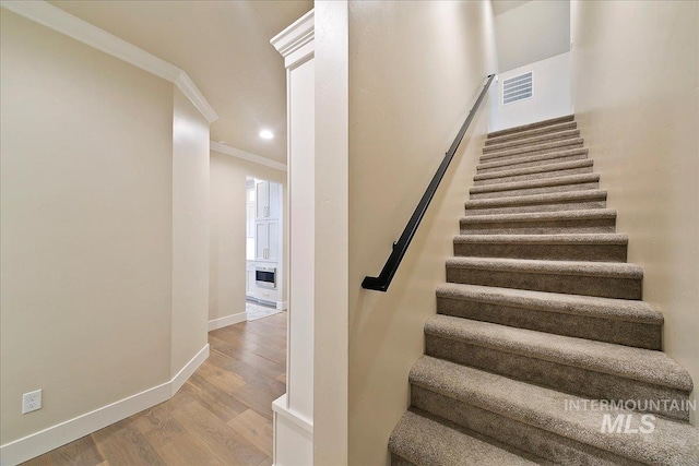 staircase featuring ornamental molding and hardwood / wood-style floors