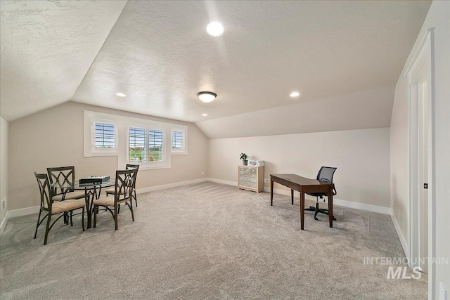 carpeted home office with a textured ceiling and lofted ceiling