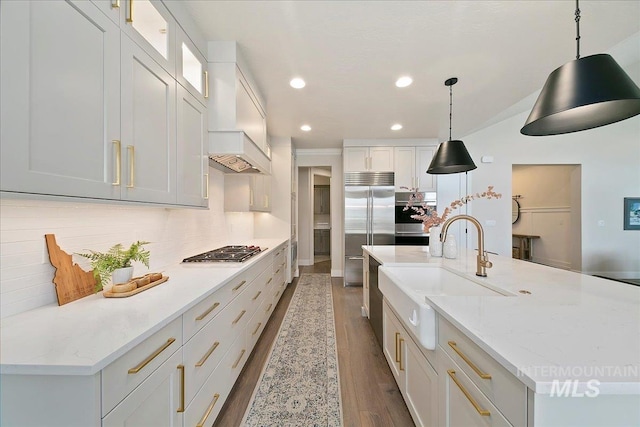 kitchen featuring stainless steel appliances, pendant lighting, white cabinets, backsplash, and sink