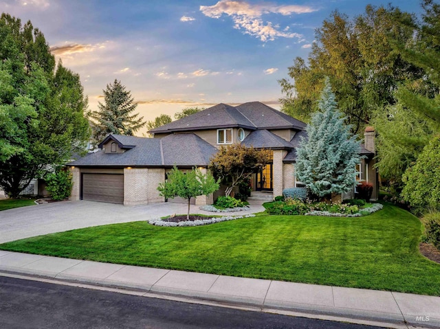 view of front of home with a garage and a lawn