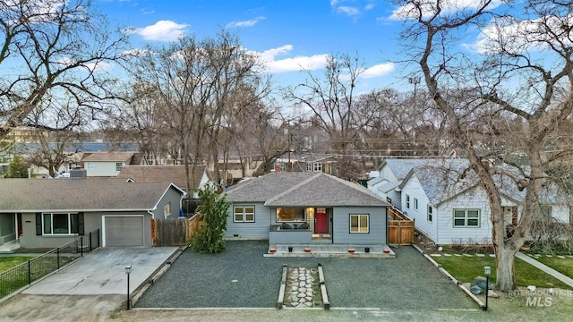 view of front of house with concrete driveway, fence, a garage, and a residential view