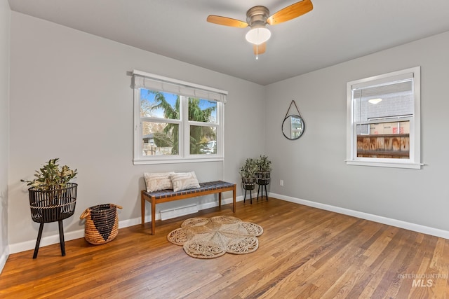 sitting room with hardwood / wood-style flooring, baseboards, and ceiling fan