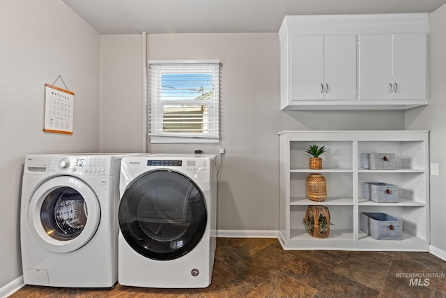 washroom featuring washer and dryer, baseboards, and cabinet space